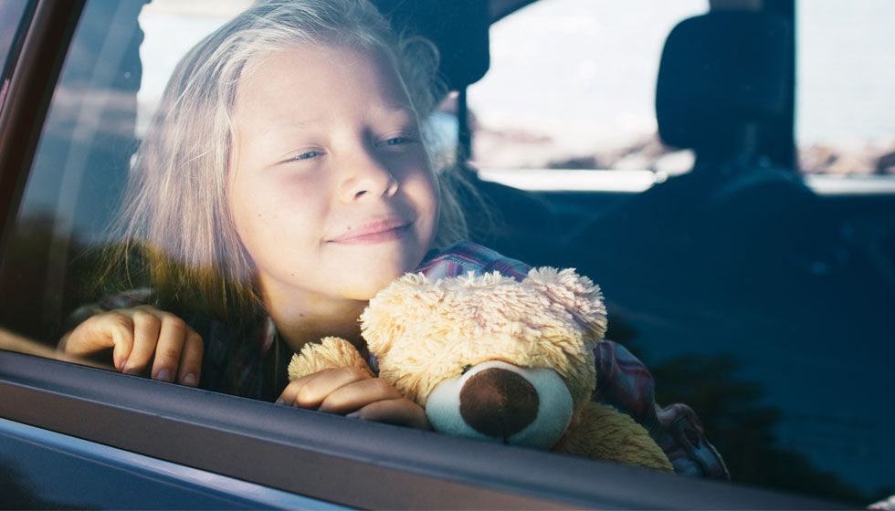 girl with bear looking out a window
